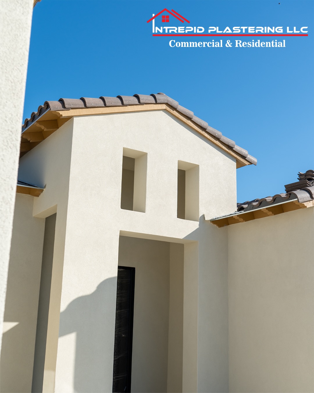 Freshly plastered stucco home exterior under a clear blue sky, with the Intrepid Plastering LLC logo across the top.